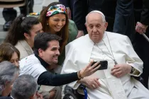 El Papa Francisco se toma una foto junto a varios jóvenes durante una audiencia.