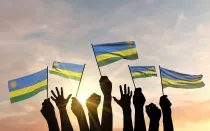 Siluetas de manos levantadas ondeando banderas de Ruanda