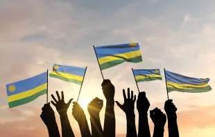 Siluetas de manos levantadas ondeando banderas de Ruanda Crédito: Ink Drop/ Shutterstock
