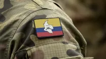 Bandera de las Fuerzas Armadas Revolucionarias de Colombia (FARC) con uniforme militar. Crédito: Shutterstock.