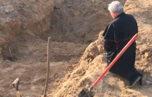 El Cardenal Krajewsi, enviado del Papa Francisco a Ucrania por Semana Santa, reza ante una fosa comu00fan cerca de Kiev. Cru00e9dito: Vatican Media 