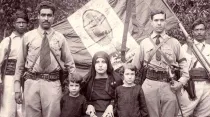 Cristeros junto a familiares, con la bandera de México detrás con la imagen de la Virgen de Guadalupe como escudo. Foto: Dominio público.