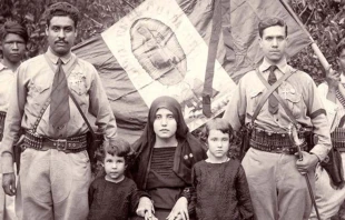 Cristeros junto a familiares, con la bandera de Mu00e9xico detru00e1s con la imagen de la Virgen de Guadalupe como escudo. Foto: Dominio pu00fablico. 