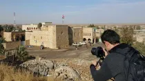 Joven tomando una fotografía de una casa dañada en Qaraqosh (Irak) / Foto: Cortesía P. Georges Jahola 