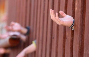 Manos a travu00e9s del muro fronterizo de Estados Unidos y Mu00e9xico. Foto: Flickr Boston Catholic (CC-BY-ND-2.0). 