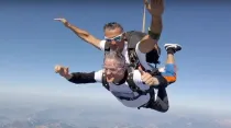 Mons. Xavier Malle en un momento del salto en paracaídas. Crédito: Captura Pantalla Youtube. 