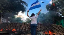 Una mujer con la bandera de Nicaragua en una barricada durante las protestas de abril. Foto: Voice of America / dominio público