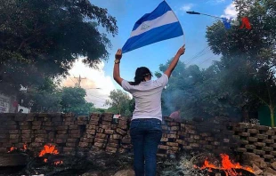 Una mujer con la bandera de Nicaragua en una barricada durante las protestas de abril de 2018. Foto: Voice of America / Dominio pu00fablico. 