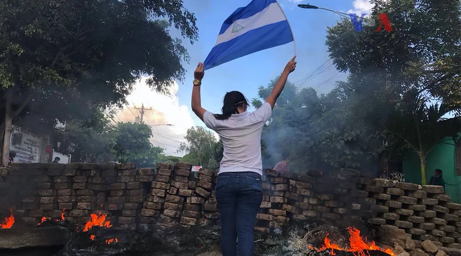 Joven sostiene la bandera de Nicaragua en medio de protestas y represión policial. Foto: Voice of America / Dominio público.