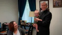 Deanna Johnston, directora de vida familiar del Instituto San Felipe, observa cómo Mons. Joseph Strickland sostiene a su bebé / Crédito: Cortesía del Instituto San Felipe