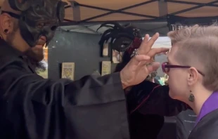 Organizadores del festival pintan cruces invertidas en la frente de los asistentes. Cru00e9dito: Captura de vu00eddeo 