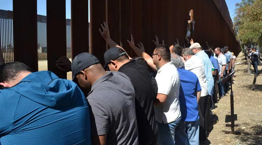 Sacerdotes scalabrinianos rezan ante muro que separa México y Estados Unidos. Crédito: Cortesía Casa del Migrante en Tijuana.