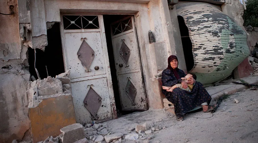 Mujer siria se sienta con su nieto frente a un edificio dañado de la aldea de Treimsa (Siria) / Crédito: Fondo Andaluz de Municipios para la Solidaridad Internacional (CC BY-NC-ND 2.0)
