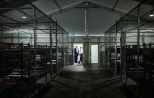 Filas de literas llenan el interior de la llamada instalación de detención “Alligator Alcatraz” en los Everglades de Florida (Estados Unidos), un centro de entrenamiento reutilizado que ahora está designado para albergar inmigrantes. El presidente estadounidense Donald Trump aparece al fondo durante una visita al lugar el 1 de julio de 2025, que ha suscitado críticas del obispo Frank Dewane y otros líderes católicos. Crédito: The White House / Dominio público.