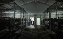 Filas de literas llenan el interior de la llamada instalación de detención “Alligator Alcatraz” en los Everglades de Florida (Estados Unidos), un centro de entrenamiento reutilizado que ahora está designado para albergar inmigrantes. El presidente estadounidense Donald Trump aparece al fondo durante una visita al lugar el 1 de julio de 2025, que ha suscitado críticas del obispo Frank Dewane y otros líderes católicos.