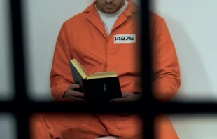 Imagen referencial de una persona en la cárcel leyendo la Biblia. Crédito: Motortion / Canva