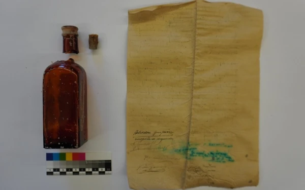 La botella y el documento tras ser procesados por un arqueólogo. Crédito: Diócesis de Alcalá de Henares.