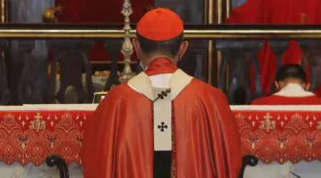 Un cardenal católico, arrodillado durante una celebración litúrgica.