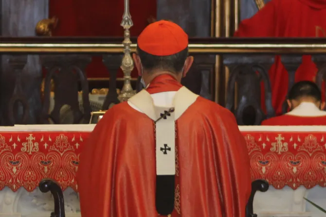 Un cardenal católico, arrodillado durante una celebración litúrgica.