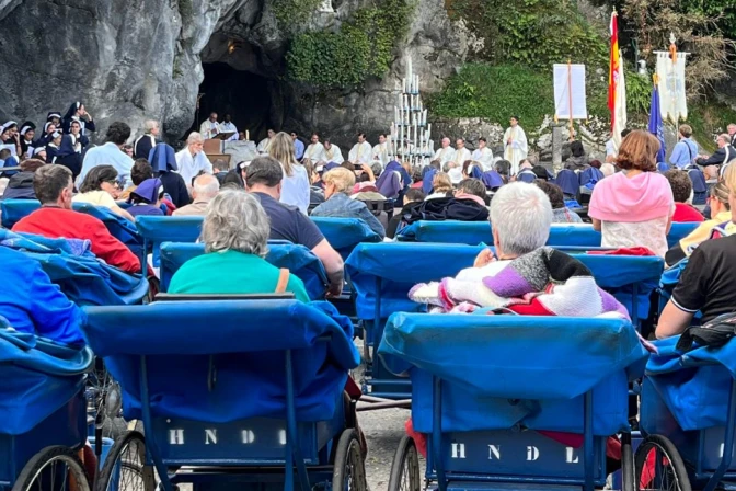 Peregrinos asisten desde los icónicos carros azules a la Misa en la gruta del Santuario de Lourdes (Francia).