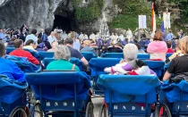 Peregrinos asisten desde los icónicos carros azules a la Misa en la gruta del Santuario de Lourdes (Francia).