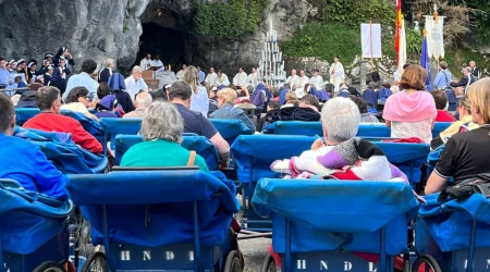 Peregrinos asisten desde los icónicos carros azules a la Misa en la gruta del Santuario de Lourdes (Francia).