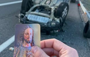 Jose María Mayoral sujeta la estampa del Sagrado Corazón de Jesús junto al lugar del accidente Crédito: Cortesía de Jose María Mayoral