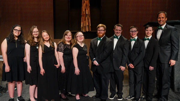 El coro de Amigos del Club 21 posa para una foto junto a Jared Anderson (derecha) tras una actuación en 2024. Crédito: Cortesía de Amigos del Club 21