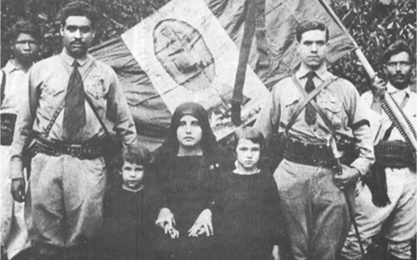 Cristeros junto a familiares, con la bandera de México detrás con la imagen de la Virgen de Guadalupe como escudo.?w=200&h=150