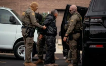 Una persona detenida es llevada a un estacionamiento en el extremo norte de Chicago antes de ser trasladada a un centro del Servicio de Inmigración y Control de Aduanas (ICE) el 31 de octubre de 2025.