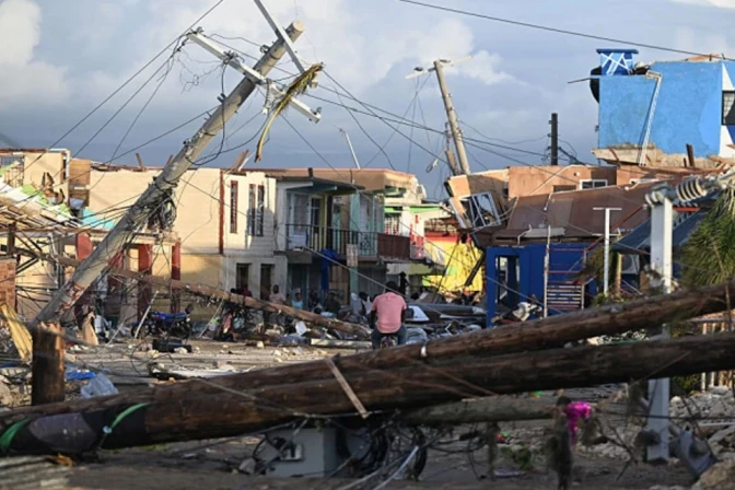 Postes de luz caídos mientras un hombre recorre en bicicleta el barrio devastado de North Street tras el paso del huracán Melissa, en Black River, Jamaica, el 29 de octubre de 2025.