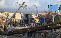 Postes de luz caídos mientras un hombre recorre en bicicleta el barrio devastado de North Street tras el paso del huracán Melissa, en Black River, Jamaica, el 29 de octubre de 2025.