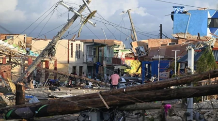 Postes de luz caídos mientras un hombre recorre en bicicleta el barrio devastado de North Street tras el paso del huracán Melissa, en Black River, Jamaica, el 29 de octubre de 2025.