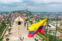 Bandera ecuatoriana en la cima de la colina de Santa Ana con una iglesia y la ciudad de Guayaquil visible en el fondo.