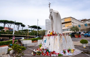 Estatua de San Juan Pablo II a las afueras del Policlínico Agostino Gemelli, a cuyos pies los fieles colocan velas y flores para pedir por la salud del Papa Francisco. Crédito: Daniel Ibáñez / EWTN News.