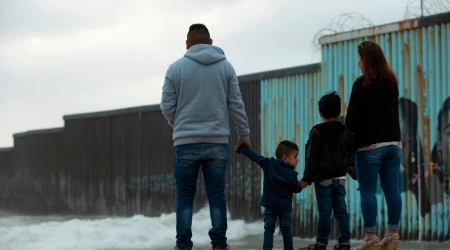 Una familia permanece frente al muro de la frontera entre Estados Unidos y México.