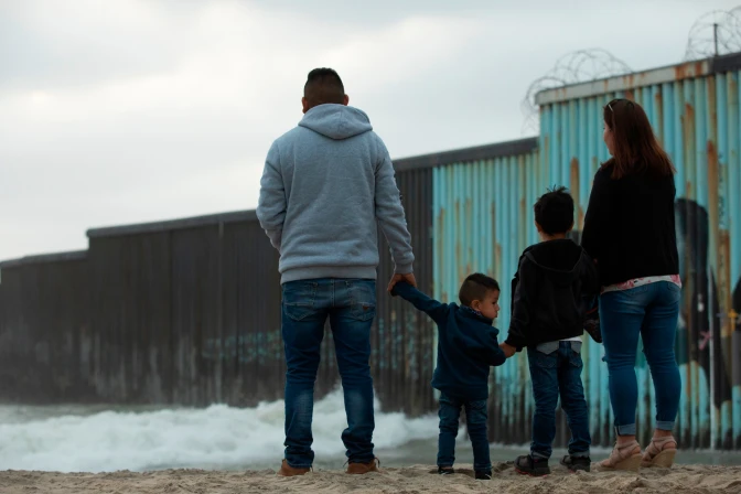 Una familia permanece frente al muro de la frontera entre Estados Unidos y México.