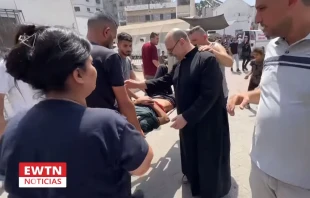 El P. Gabriel Romanelli, el único párroco católico de Gaza, bendice a un herido. Crédito: EWTN Noticias.
