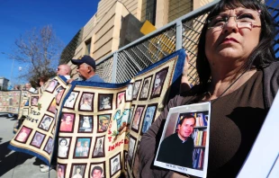 Esther Miller sostiene una fotografía y los documentos publicados sobre el padre Michael Nocita, mientras las víctimas y sus seguidores sostienen colchas con retratos de niños abusados, reunidos frente a la Catedral de Nuestra Señora de los Ángeles en Los Ángeles el 1 de febrero de 2013. Crédito: FREDERIC J. BROWN/AFP vía Getty Images.