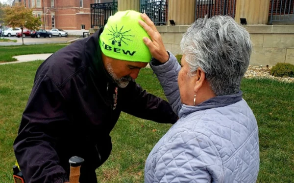 El P. Gary reza con una señora en su travesía. Crédito: Gary Graf.