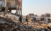 Palestinos desplazados caminan entre los escombros de las casas destruidas por la guerra entre Israel y Hamás, en Khan Younis, Franja de Gaza, el 18 de noviembre de 2024.