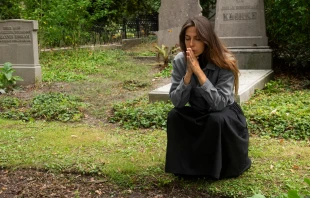 Imagen referencial de una mujer rezando en un cementerio. Crédito: Freepik