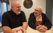 De izq. a der.: El P. Joe Krupp se ríe mientras su padre, Gordon Krupp, sonríe en la casa parroquial que comparten. Crédito: Cortesía de Church of the Holy Spirit en Grand Blanc, Míchigan (Estados Unidos).