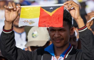 Joven de Timor Oriental levanta la bandera del Vaticano junto a la de su país en la Misa del Papa Francisco en Taci Tolu Crédito: Daniel Ibáñez/ EWTN News