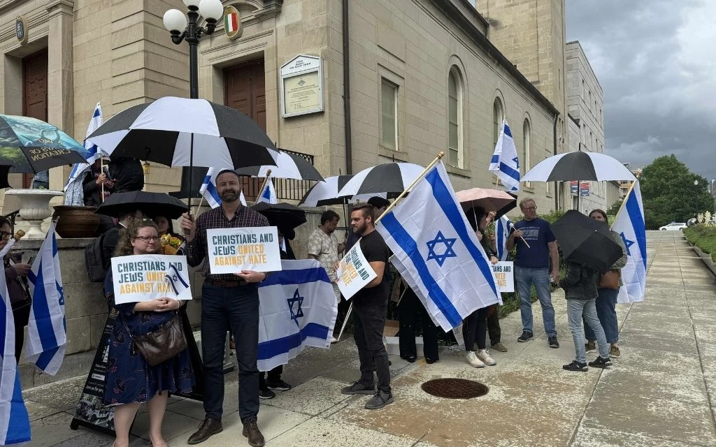 Los participantes en una vigilia vespertina del 22 de mayo de 2025 para honrar las dos vidas perdidas en un atentado frente al Museo Judío Capital en Washington D.C., la noche anterior, sostienen carteles con la leyenda "Cristianos y judíos unidos contra el odio".?w=200&h=150