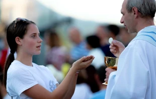 Una fiel recibe la Eucaristía de manos de un sacerdote. Crédito: Daniel-Ibáñez.