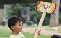 Un niño sostiene un cartel con una imagen del Espíritu Santo.