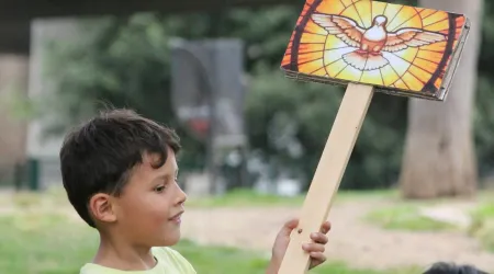 Un niño sostiene un cartel con una imagen del Espíritu Santo.