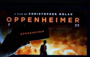 Logo de la película Oppenheimer y afiche en una pantalla. Crédito: Rokas Tenys - Shutterstock