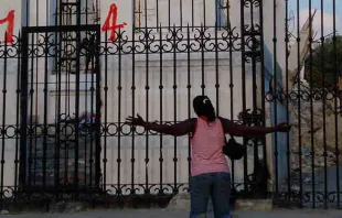Una mujer haitiana arrodillada en oración frente a la Catedral de Puerto Príncipe, capital del país. Crédito: ACN.